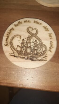 A laser engraved wooden coaster featuring a classic tall ship caught in kraken tentacles, paired with a perfectly sarcastic phrase.
